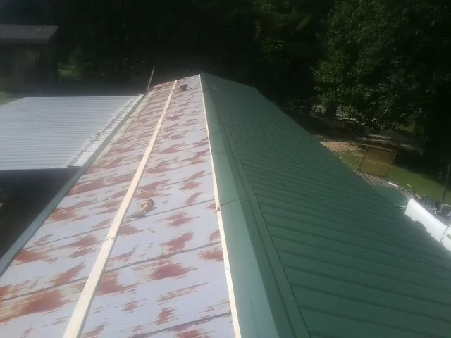 Old rusted panels beside newly installed green metal roofing — Wind Damage Roof Repair by Roofing Brothers in Newmarket