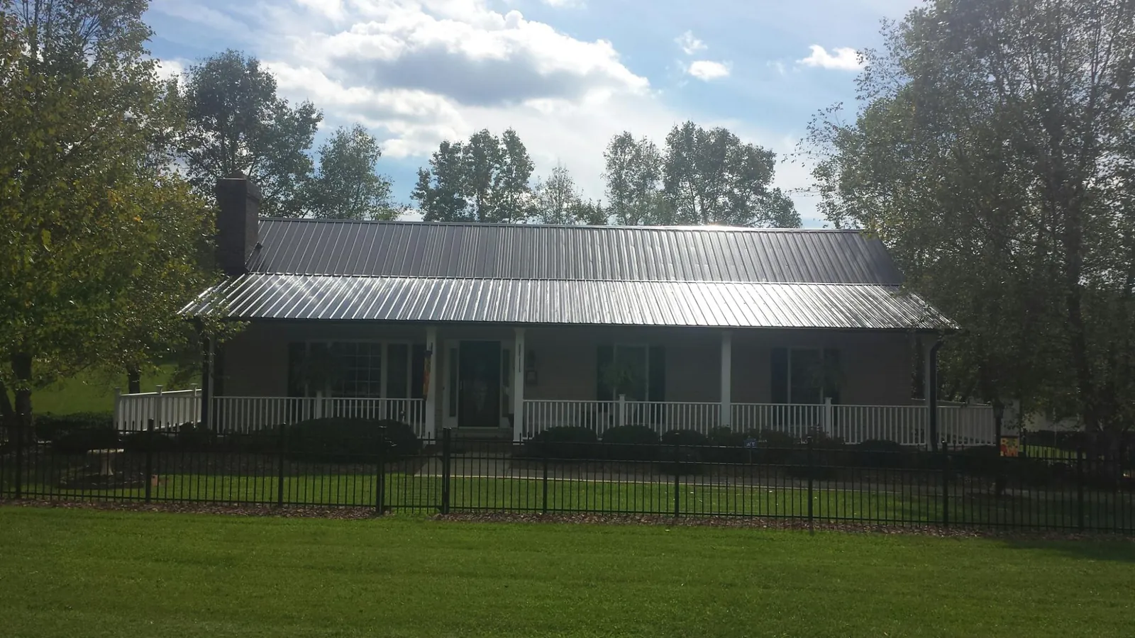 Gray metal roof on a brick ranch with a full width front porch — Gutter Guard Installation work by our crew in Newmarket