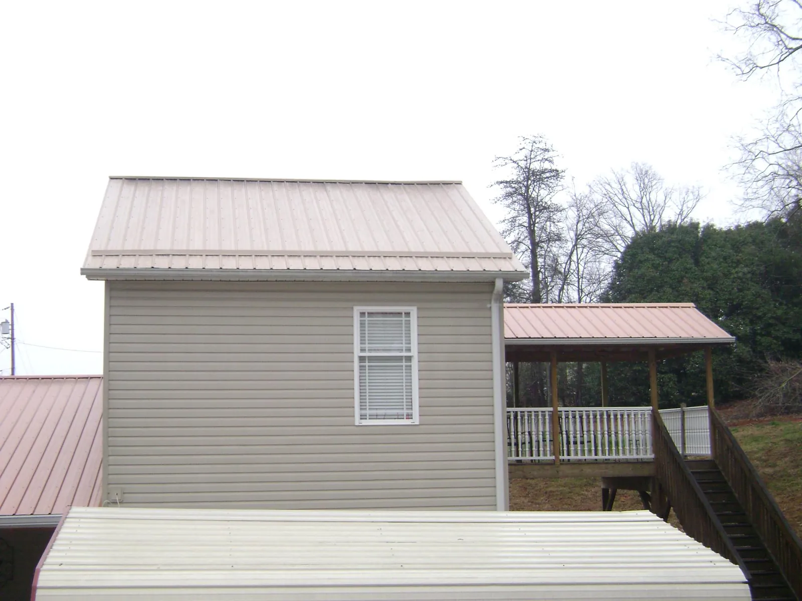 Tan metal roofs on a two story addition and attached porch, from a Roof Replacement job in Newmarket